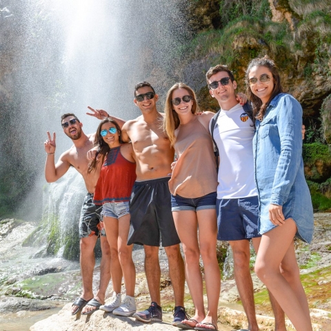 A group of friends enjoying the waterfall, part of the hot springs tour