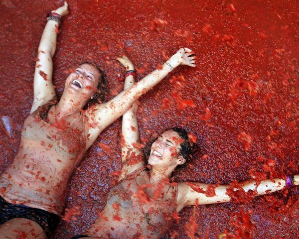 Two girls laughing on the ground at Tomatina in Valencia
